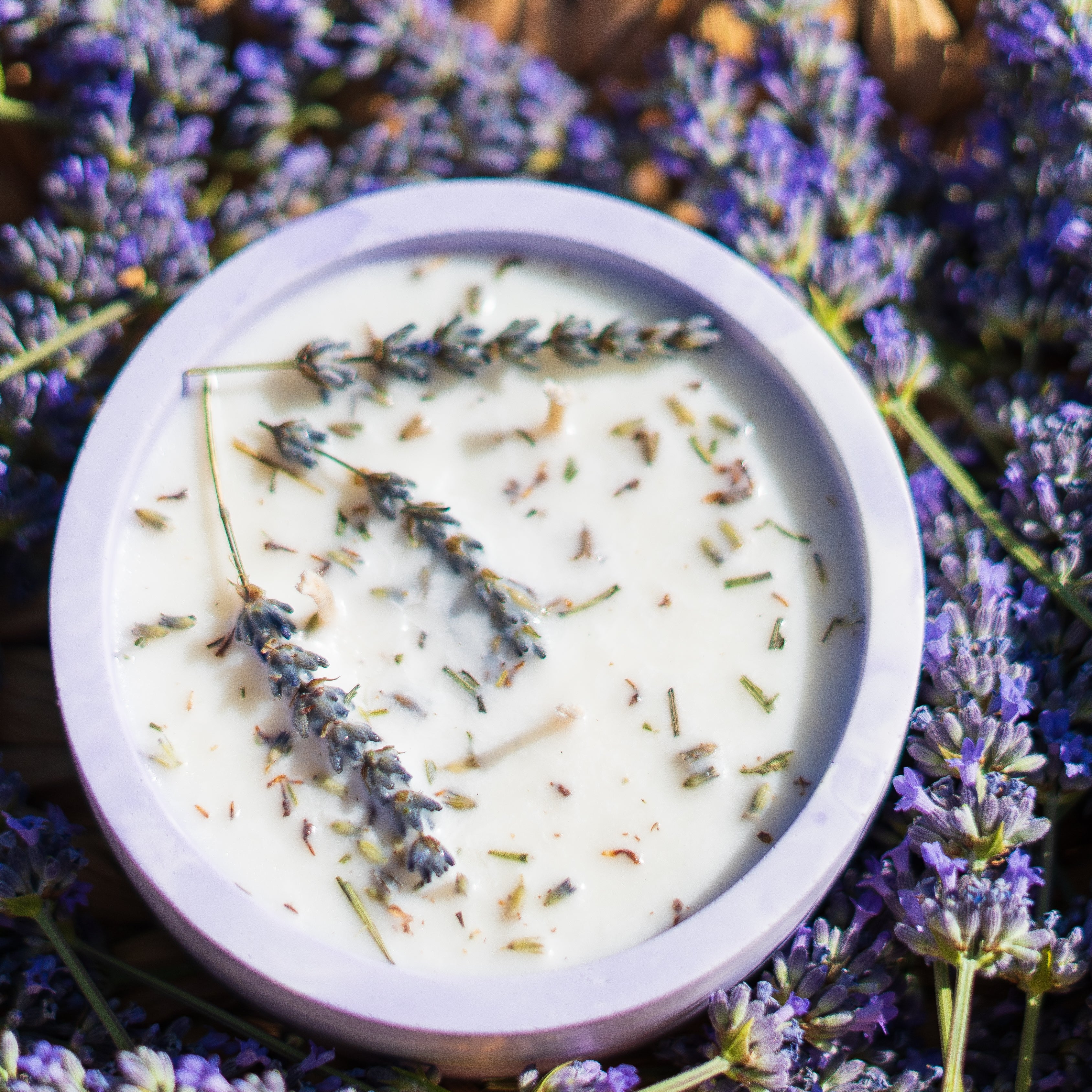 Candle with lavender flowers in a basket of lavender flowers