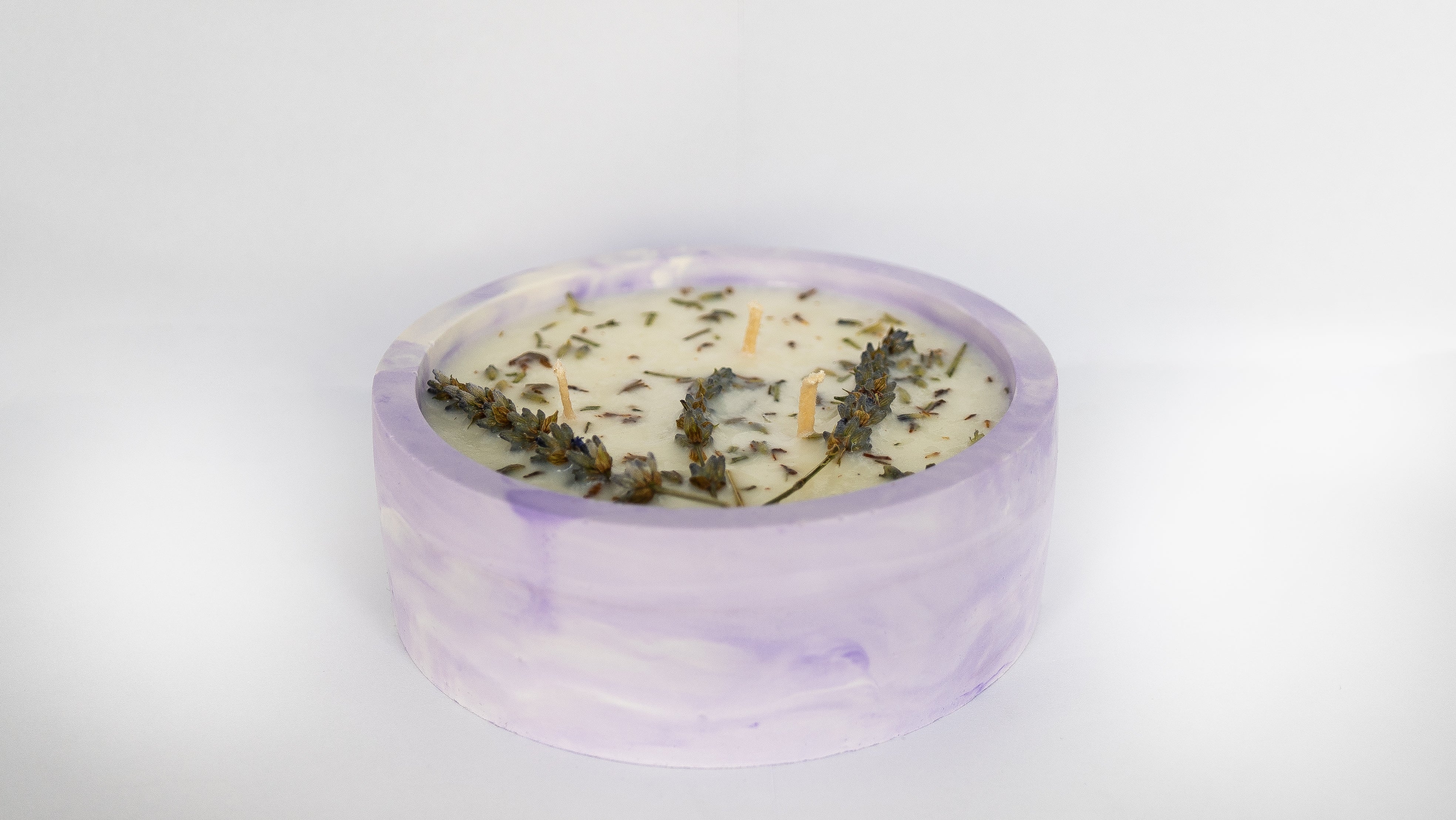 Candle with lavender flowers in a basket of lavender flowers